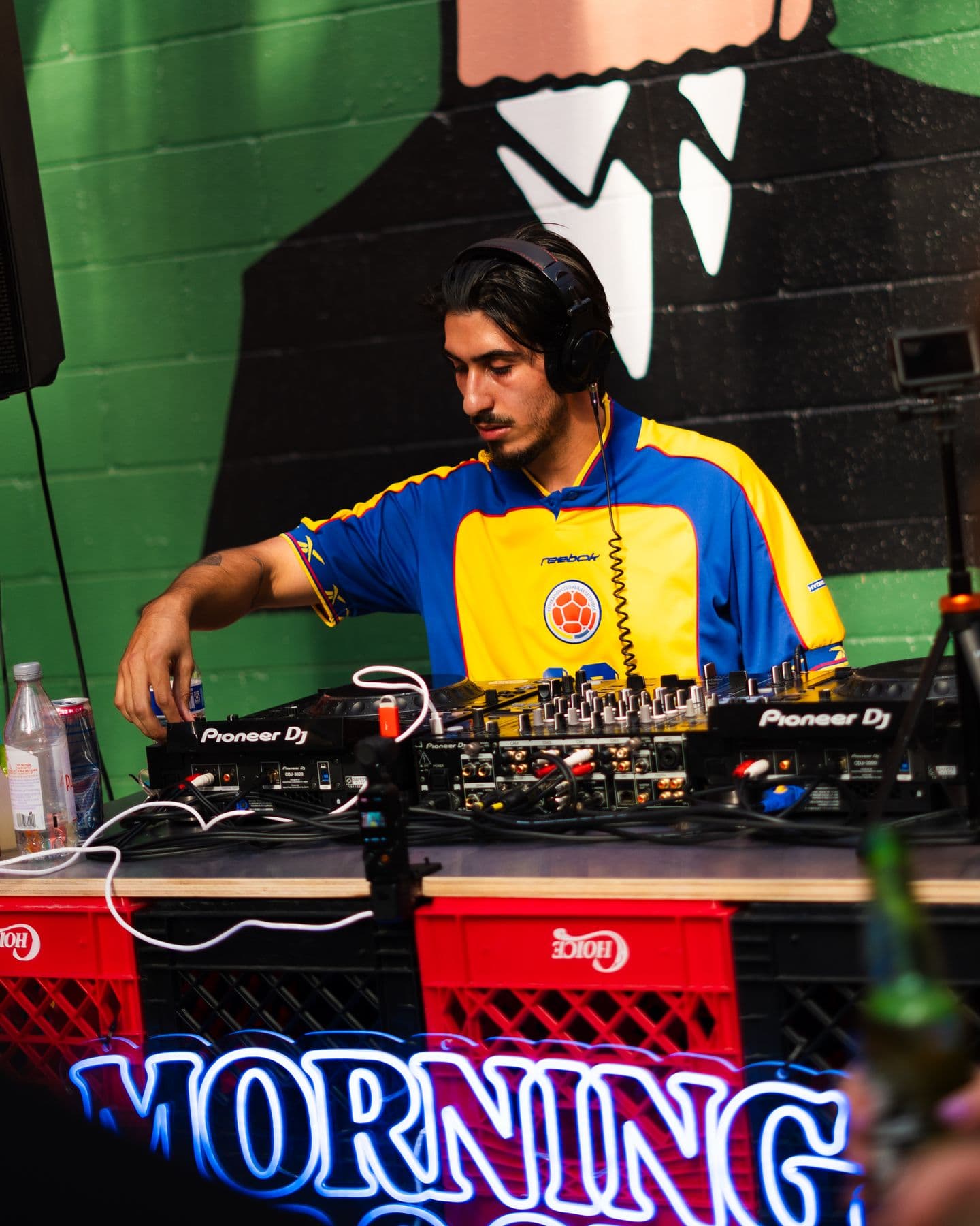 A DJ behind the Morning Groove banner under the mural